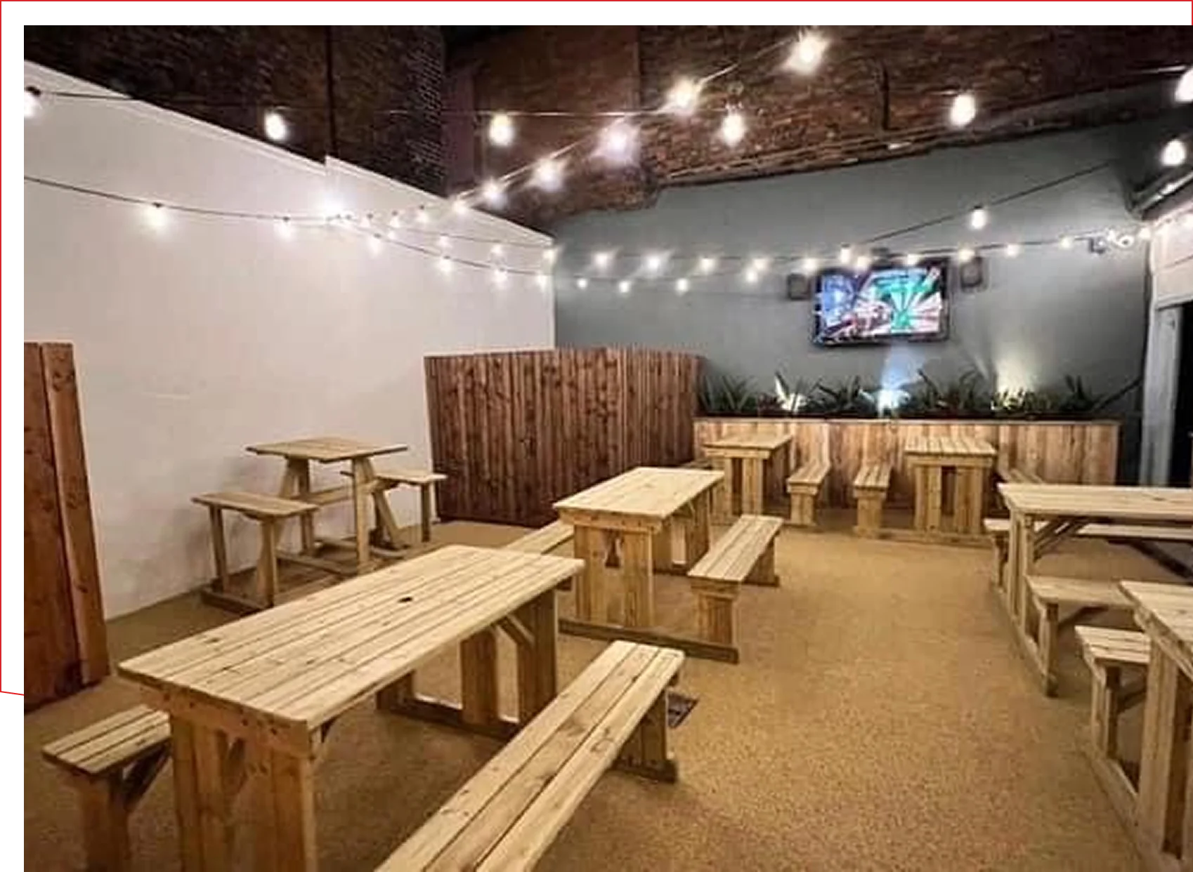Frame 1618873881 (4) Outdoor patio with wooden tables and lights.