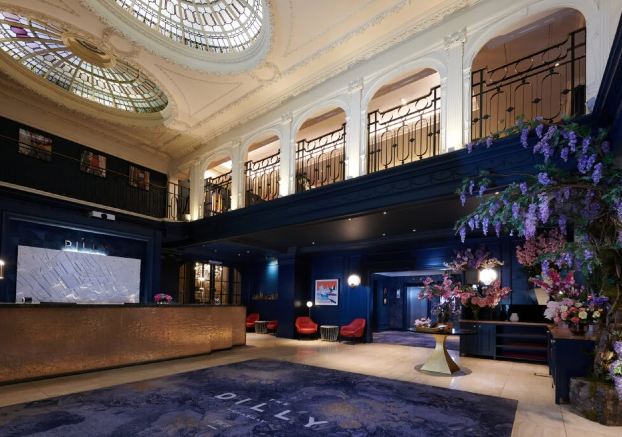 Elegant hotel lobby with ornate ceiling and flowers.